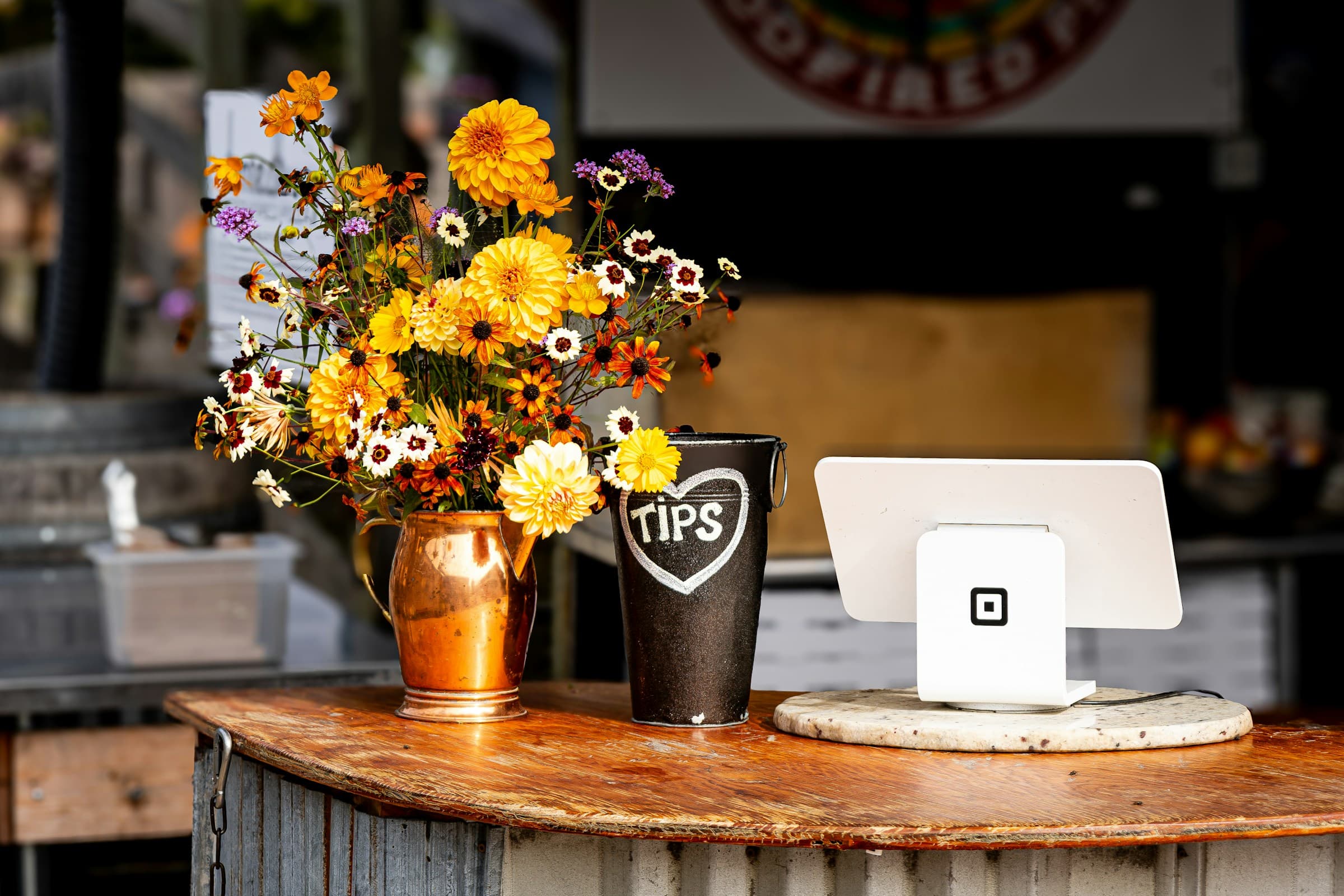 Comptoir de boutique en bois avec terminal de paiement et bouquet de fleurs, lumière chaude